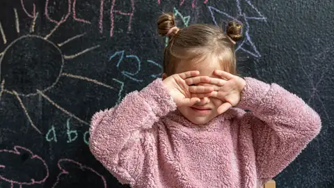 Una niña se tapa la cara con las manos Una niña se tapa la cara con las manos