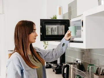 Mujer usando el microondas Mujer usando el microondas