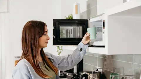 Mujer usando el microondas Mujer usando el microondas