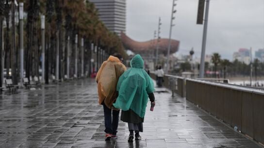 Dos personas caminan bajo la lluvia en Barcelona