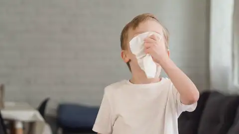 Un niño con un pañuelo para sonarse. Un niño con un pañuelo para sonarse.
