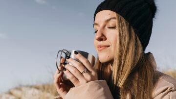 Mujer en invierno con una taza de bebida caliente y frente al sol 