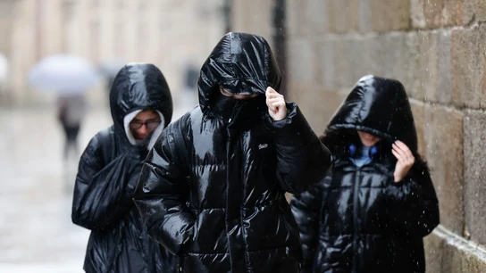 Tres personas protegiéndose de la lluvia en Galicia Tres personas protegiéndose de la lluvia en Galicia