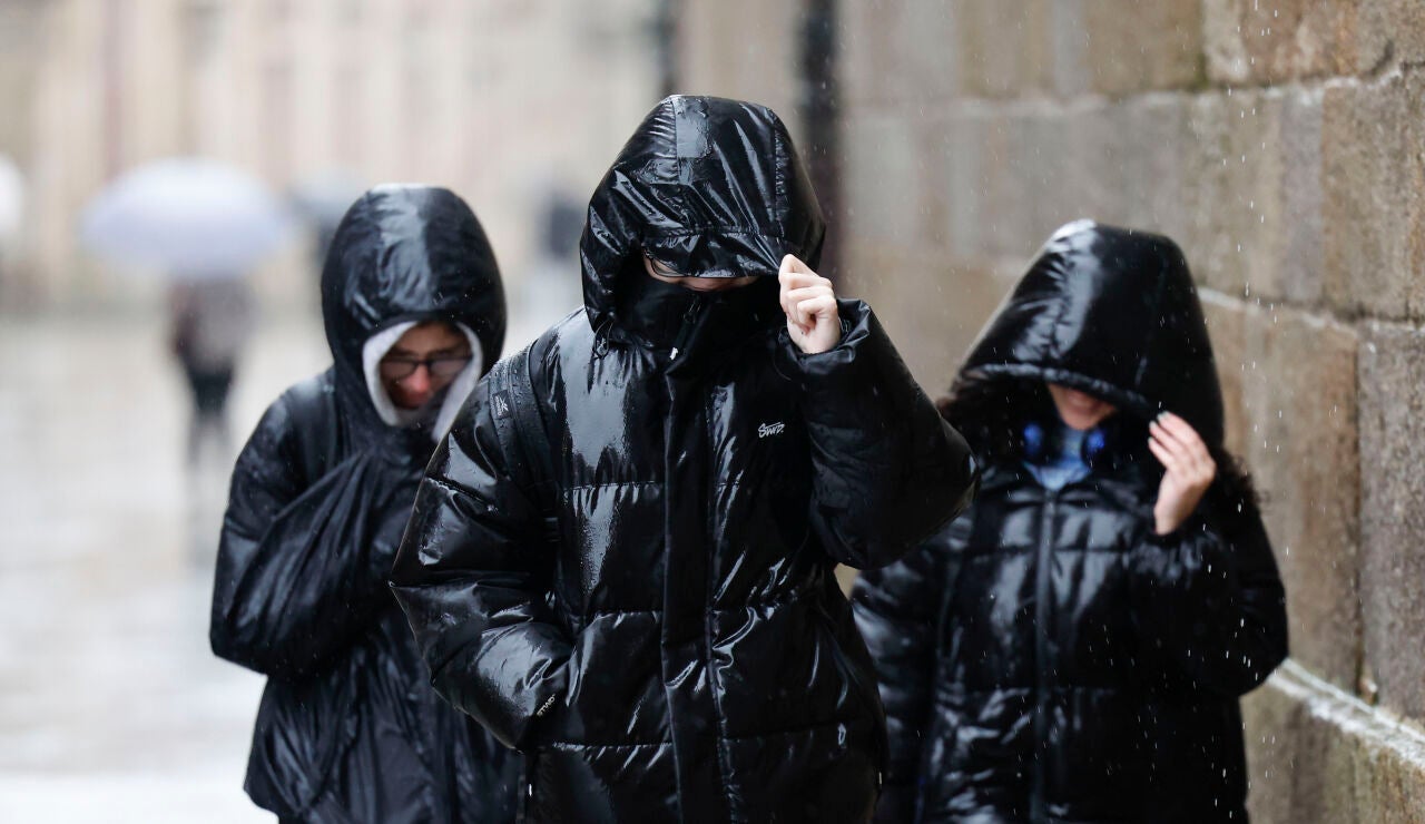 Tres personas protegi&eacute;ndose de la lluvia en Galicia