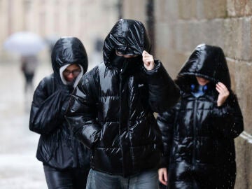 Tres personas protegi&eacute;ndose de la lluvia en Galicia