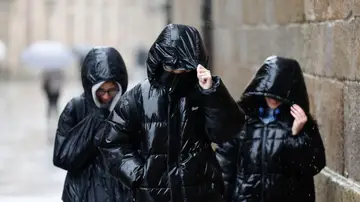 Tres personas protegiéndose de la lluvia en Galicia Tres personas protegiéndose de la lluvia en Galicia