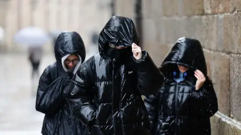 Tres personas protegiéndose de la lluvia en Galicia Tres personas protegiéndose de la lluvia en Galicia