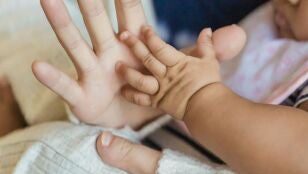 Imagen de archivo de la mano de una mujer y de un beb&eacute;.