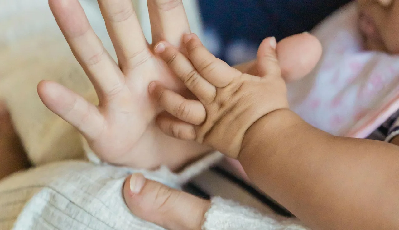 Imagen de archivo de la mano de una mujer y de un bebé.
