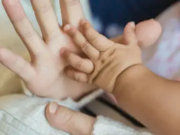 Imagen de archivo de la mano de una mujer y de un bebé. Imagen de archivo de la mano de una mujer y de un bebé.