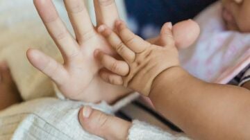 Imagen de archivo de la mano de una mujer y de un beb&eacute;.