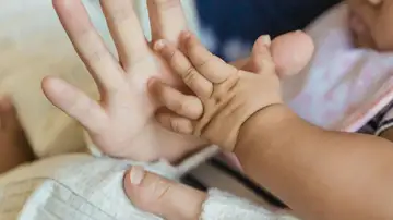 Imagen de archivo de la mano de una mujer y de un bebé. Imagen de archivo de la mano de una mujer y de un bebé.