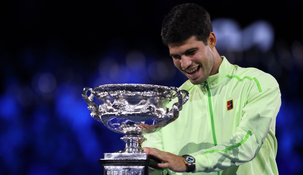 Carlos Alcaraz sonr&iacute;e ante el trofeo del Open de Australia