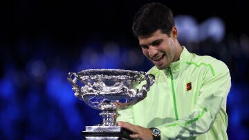 Carlos Alcaraz sonr&iacute;e ante el trofeo del Open de Australia