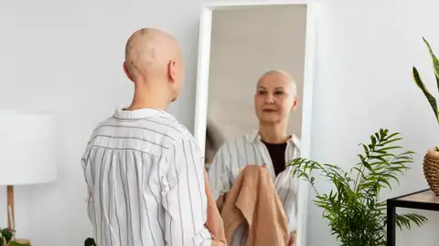Una mujer en tratamiento contra el cáncer se mira al espejo Una mujer en tratamiento contra el cáncer se mira al espejo