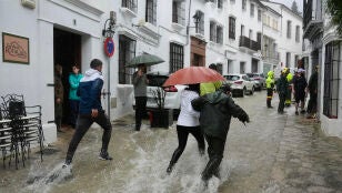 Vecinos de Grazalema corren por una calle inundada debido a las intensas lluvias que se registran este mi&eacute;rcoles en la localidad gaditana