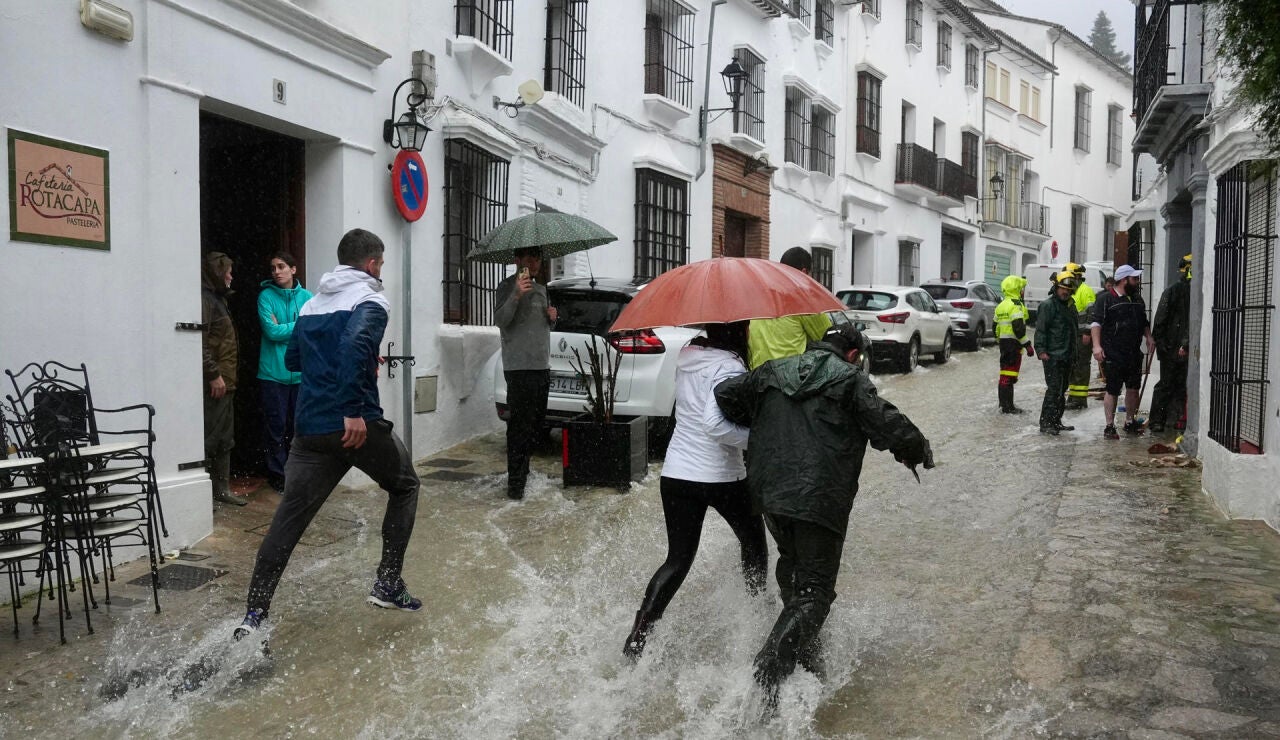 Vecinos de Grazalema corren por una calle inundada debido a las intensas lluvias que se registran este mi&eacute;rcoles en la localidad gaditana