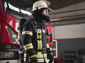 Bombero al lado de un cami&oacute;n de bomberos