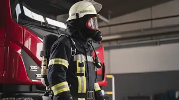 Bombero al lado de un camión de bomberos Bombero al lado de un camión de bomberos