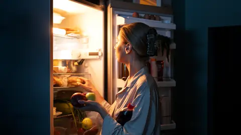 Mujer cogiendo comida de la nevera Mujer cogiendo comida de la nevera