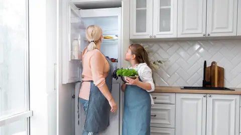 Madre e hija cogiendo comida de la nevera Madre e hija cogiendo comida de la nevera