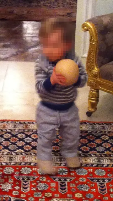 Niño jugando con una pelota en forma de pecho humano Niño jugando con una pelota en forma de pecho humano