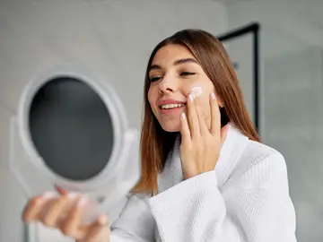Mujer aplicándose crema en la cara Mujer aplicándose crema en la cara
