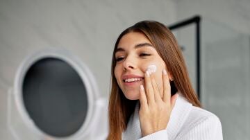 Mujer aplic&aacute;ndose crema en la cara