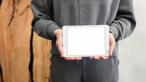 Un joven sosteniendo un Ipad Un joven sosteniendo un Ipad