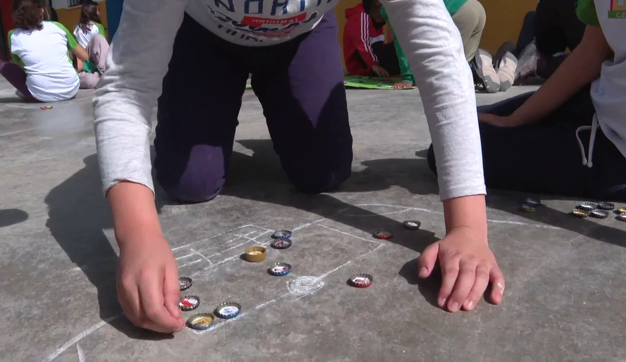 El fútbol chapas ha vuelto al patio de un colegio sevillano, los alumnos han aprendido a jugar y se ganan las chapas por su buen comportamiento