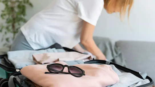 Mujer poniendo ropa en la maleta Mujer poniendo ropa en la maleta