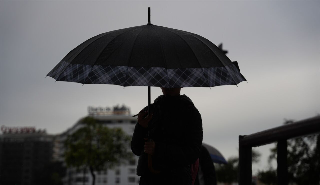Peatones se protegen de la lluvia bajo sus paraguas.