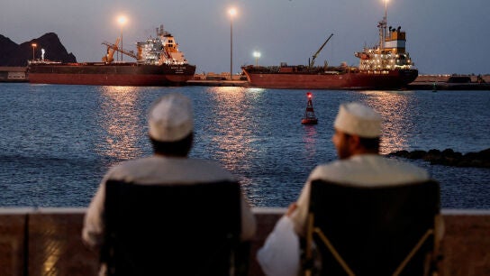 Dos hombres observan buques anclados en Mascate, Om&aacute;n, ante el cierre de Ormuz, en medio del conflicto entre Estados Unidos e Israel con Ir&aacute;n, 9 de marzo de 2026