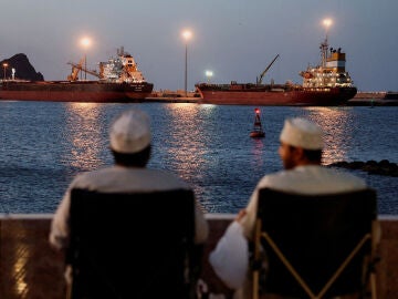 Dos hombres observan buques anclados en Mascate, Om&aacute;n, ante el cierre de Ormuz, en medio del conflicto entre Estados Unidos e Israel con Ir&aacute;n, 9 de marzo de 2026