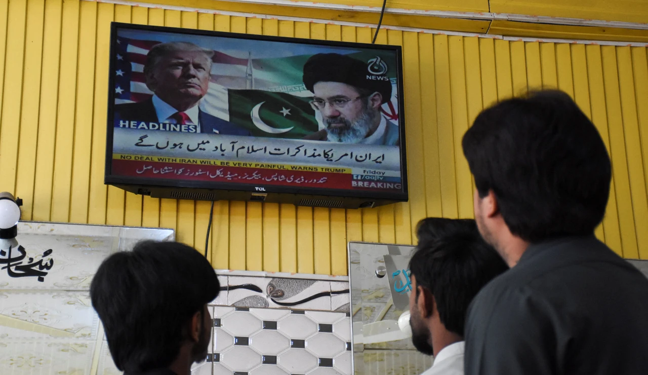 Varias personas miran hacia una pantalla de televisión con el presidente estadounidense Donald Trump y el líder supremo iraní Mojtaba Jamenei, en Islamabad, Pakistán, el 10 de abril de 2026