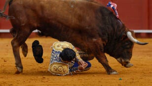 El diestro Morante de la Puebla sufre una cogida durante la novena corrida de la Feria de Abril de Sevilla