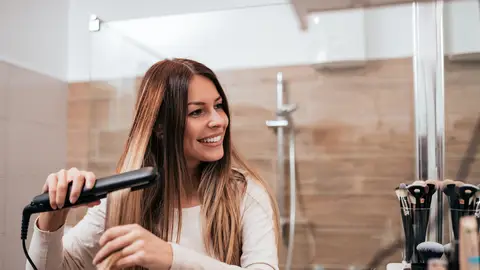 Mujer planchándose el pelo Mujer planchándose el pelo