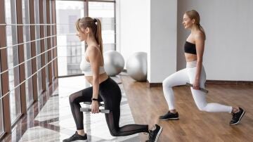 Mujeres practicando la zancada hacia atr&aacute;s alterna con mancuernas