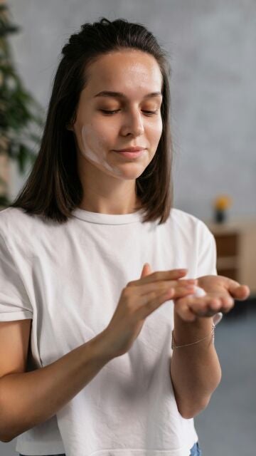 Mujer poniéndose crema solar en el rostro