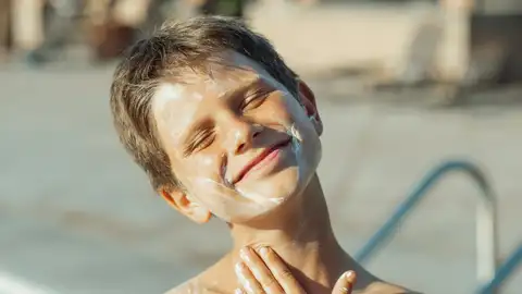 Niño poniéndose crema solar en el rostro Niño poniéndose crema solar en el rostro