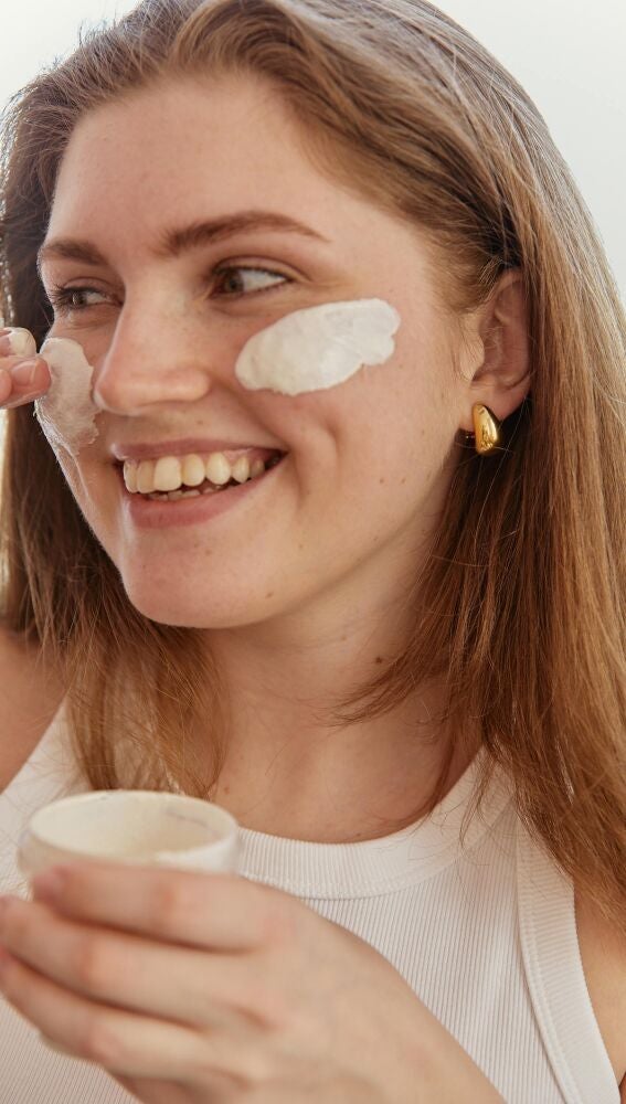 Mujer poniéndose crema solar en el rostro