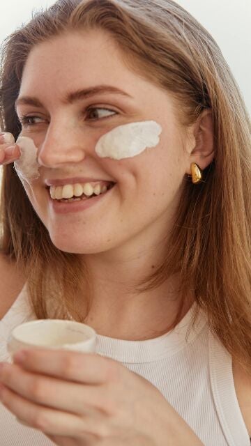 Mujer poniéndose crema solar en el rostro