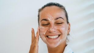 Mujer poni&eacute;ndose crema solar en el rostro