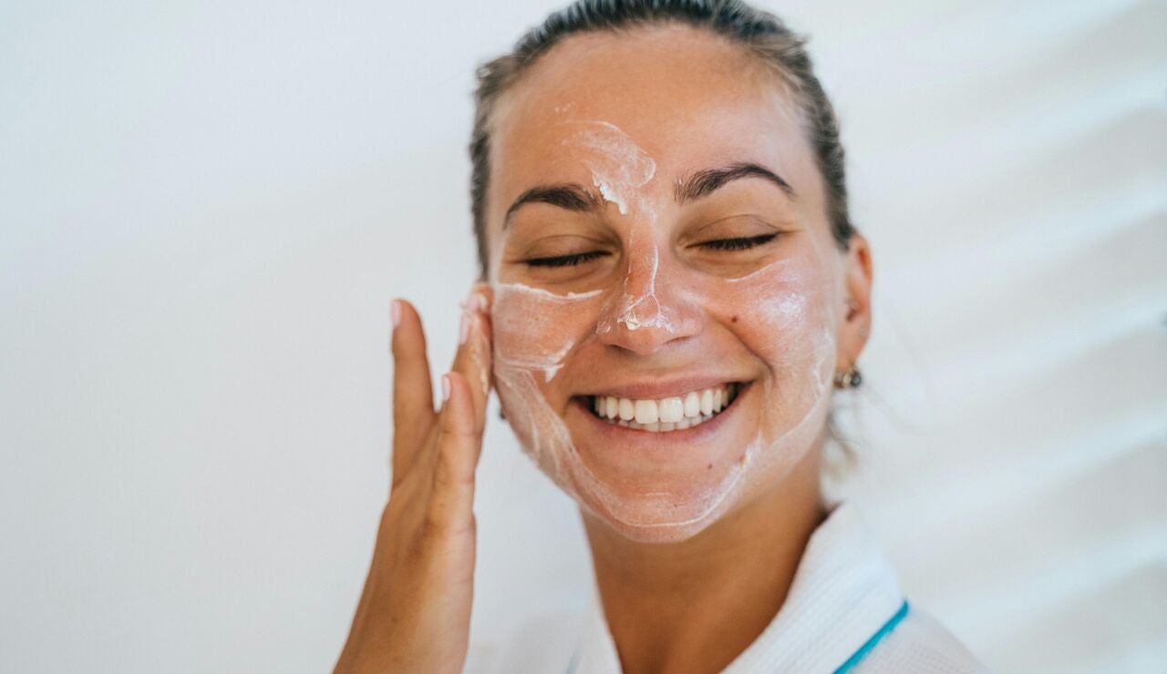 Mujer poni&eacute;ndose crema solar en el rostro