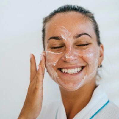 Mujer poni&eacute;ndose crema solar en el rostro