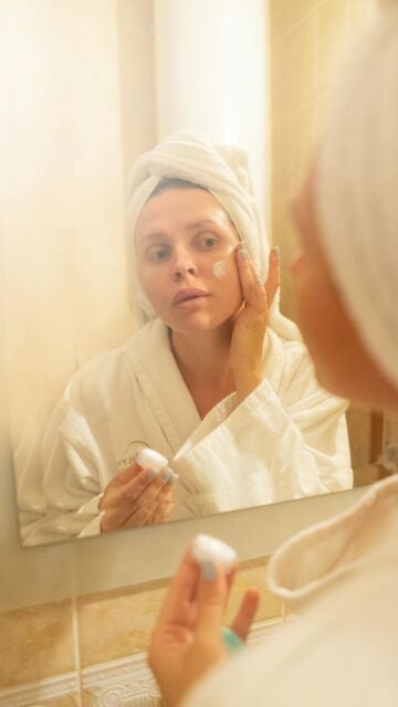 Mujer poniéndose crema solar en el rostro