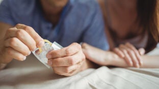 Una pareja abriendo un preservativo