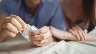 Una pareja abriendo un preservativo Una pareja abriendo un preservativo