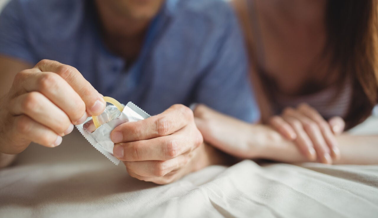 Una pareja abriendo un preservativo