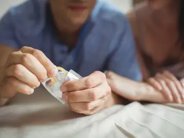Una pareja abriendo un preservativo Una pareja abriendo un preservativo